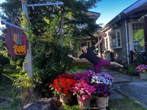 a man is jumping over flowers in front of a house at Inn Yamanami in Yamanakako