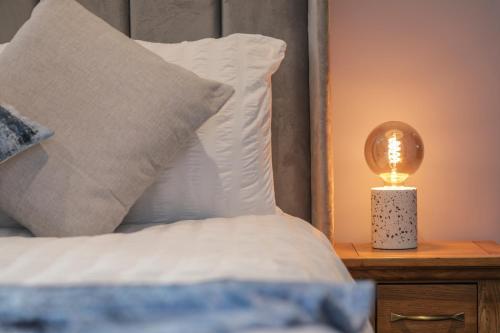 a bed with a lamp on a night stand next to it at Oak View Lodge - Deluxe Master Studio near Ipswich & Woodbridge in Playford