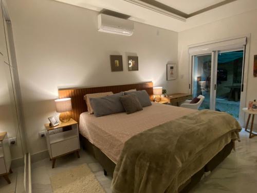 ein Schlafzimmer mit einem Bett und zwei Lampen und einem Fenster in der Unterkunft Casa aconchegante - Green Village - Praia do Cassino in Rio Grande