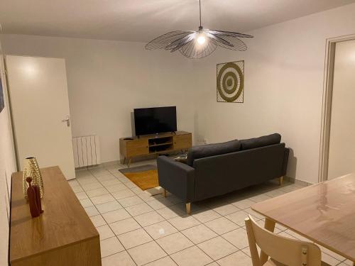 a living room with a couch and a flat screen tv at Le trait normand in Le Trait