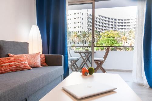 a living room with a couch and a table with a laptop at Prosurfing Apartamento in Playa del Ingles