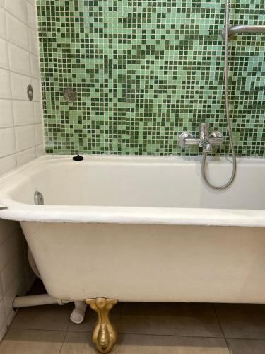a bath tub in a bathroom with a green tile wall at Casona Italia B & B in Santiago