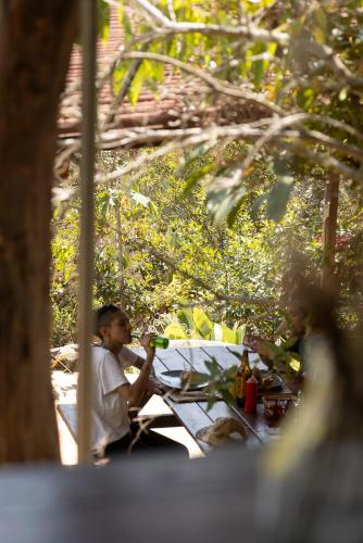 a man sitting at a table under a tree at REFUGIO LA ROCA in Los Santos