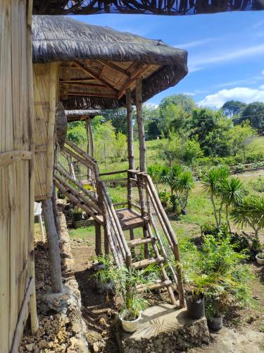 a wooden hut with a staircase and a grass roof at Tribu Kihud "Experience Simple Living" in Siquijor
