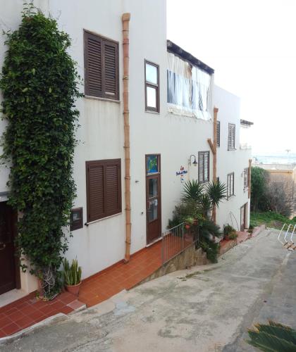 a white building with brown shutters on a street at Isoladelmiele in Marettimo