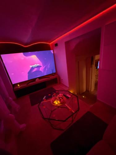 a room with a purple room with a large tv at Évasion duo, Suite Atypique privative, Hammam & Balnéo in Auriol