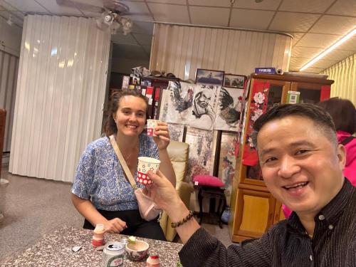 a man and a woman sitting at a table holding up cups at 集集藝術家背包客之家包層 in Jiji