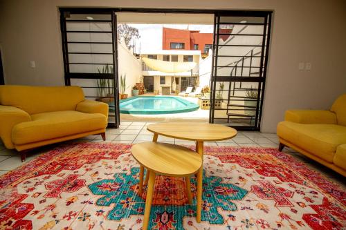 a living room with a table and two couches and a pool at Villa Azul Pool House - Centro Oaxaca in Oaxaca City