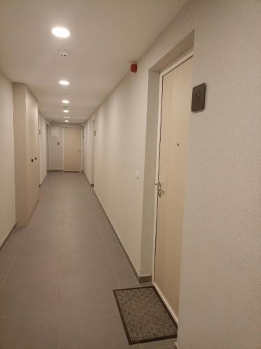 a long hallway with white walls and a door at A-Apartman in Bjelašnica