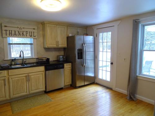a kitchen with a stainless steel refrigerator and wooden cabinets at Spacious 4 bedroom home with large yard in Wayland