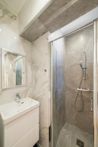 une salle de bain blanche avec une douche et un lavabo dans l'établissement Magic Apartment 4p Sacre Coeur, à Paris