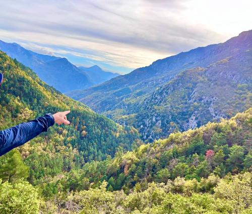 a person standing on top of a mountain pointing at a valley at La Bergerie des Cimes in Lantosque