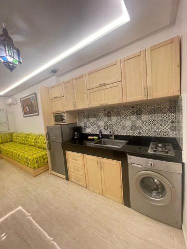 a kitchen with a washing machine and a yellow couch at cosy appartement a marrakech in Marrakech