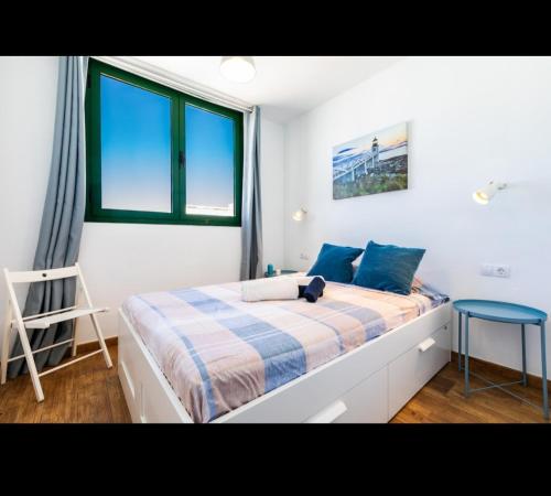 a bedroom with a bed with blue pillows and a window at La casita de Ohana in Costa Teguise