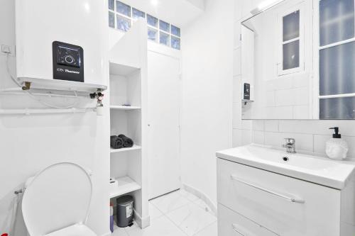 une salle de bain blanche avec des toilettes et un lavabo dans l'établissement Parisien & Cosy, à Paris