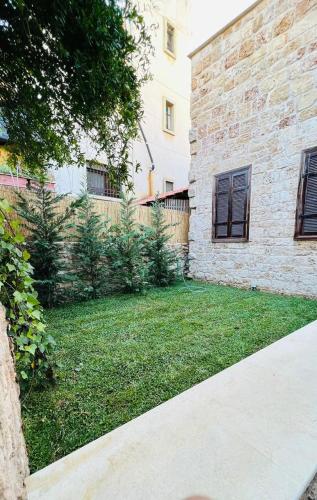 a backyard with a brick building and a yard with green grass at Batroun Old Town private duplex with garden in Batroûn