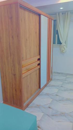 a large wooden cabinet in a room with marble floors at اهلا بيكم في بيتنا in Jazīrat al ‘Awwāmīyah