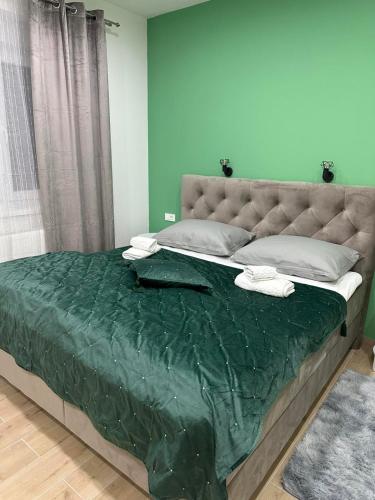 a bedroom with a large bed with a green comforter at Cibalae Residence, Self Check-In in Vinkovci