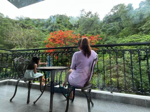 a woman and a girl sitting at a table on a balcony at Cannon Fort - The Viewpoint Hotel in Cat Ba