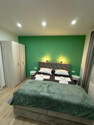a bedroom with green walls and a large bed at Cibalae Residence, Self Check-In in Vinkovci