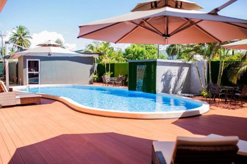 a large swimming pool with an umbrella and chairs at Hibiscus Suites And Residences in Nadi
