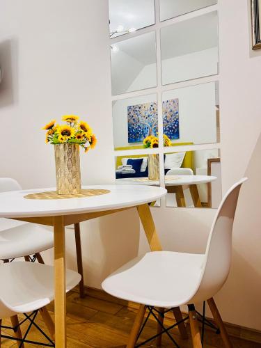 a table with white chairs and a vase with flowers at Diamond 2 in Palić