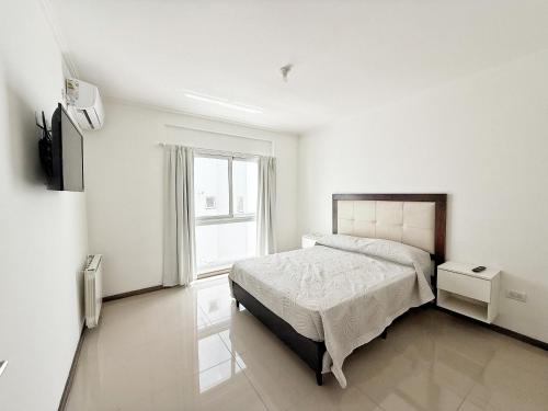 una camera da letto bianca con un letto e una finestra di VENETO V DEPARTAMENTOS a Villa Carlos Paz