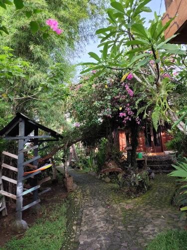 a garden with a house with trees and flowers at Bungalow T.homestay in Airsatang