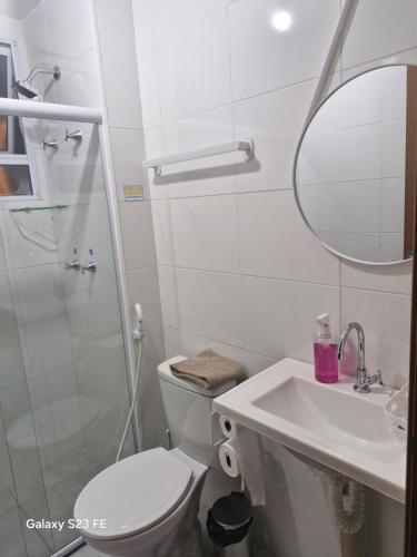 a bathroom with a toilet and a sink and a mirror at Cantinho Sunshine in Rio das Ostras