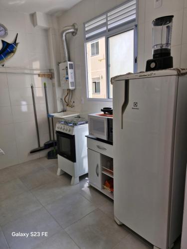 a kitchen with a refrigerator and a stove at Cantinho Sunshine in Rio das Ostras