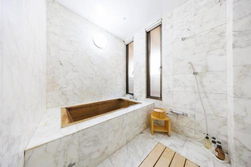 a bathroom with a tub and white marble walls at 四季亭 Shikitei in Nara