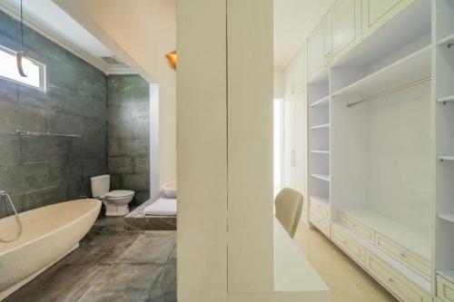 a bathroom with a tub and a toilet and a sink at Villa Karen Homestay in Uluwatu