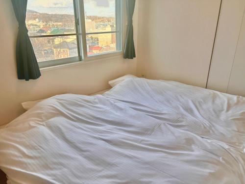 an unmade bed in a bedroom with a window at ホテル小樽キャナルビュー AMS東雲 in Otaru