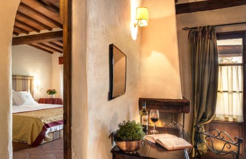 a bedroom with a bed and a table with a wine glass at Castello di Spaltenna Exclusive Resort & Spa in Gaiole in Chianti