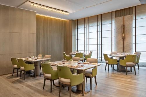 a dining room with tables and chairs and windows at Navi Mumbai Marriott in Navi Mumbai