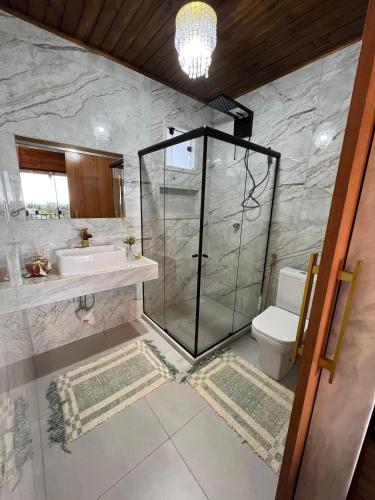 a bathroom with a shower and a sink and a toilet at Pousada Alto Colina - Chalé Siriema in Venda Nova do Imigrante