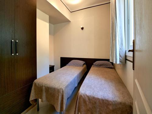 deux lits dans une petite pièce avec une fenêtre dans l'établissement Cottage in Corsica with Garden Terrace, à Sari-Solenzara