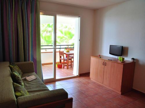 un salon avec un canapé et une télévision et un balcon dans l'établissement Apartment in Moriani-Plage by Sandy Beach, à San-Nicolao