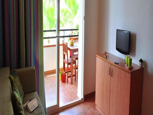 - un salon avec une télévision, une chaise et une porte coulissante dans l'établissement Apartment in Moriani-Plage by Sandy Beach, à San-Nicolao