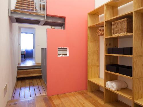 a room with a red wall and wooden shelves at Casa Levante in Syracuse