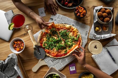 a group of people sitting around a table with a pizza at Moxy Utrecht in Utrecht