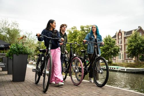 three women standing next to their bikes on a sidewalk at Moxy Utrecht in Utrecht