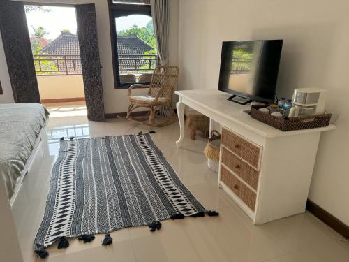 a bedroom with a desk with a television and a rug at Chakra Living Ubud in Ubud