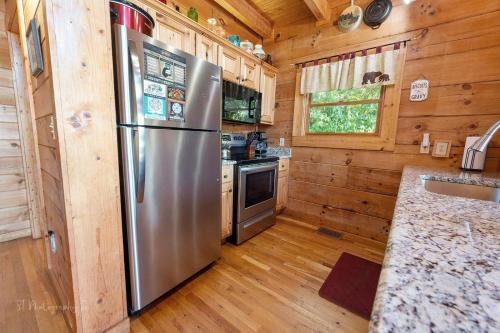 a kitchen with a stainless steel refrigerator in a log cabin at Eagles Point Cabin in Park Settlement
