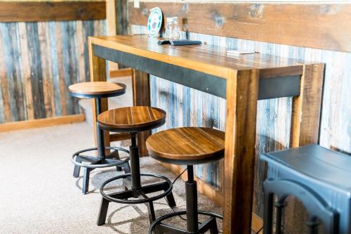 a bar with three stools in front of a wall at Eagles Point Cabin in Park Settlement