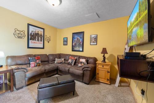 a living room with a brown couch and a flat screen tv at Eagles Point Cabin in Park Settlement