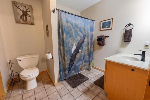 a bathroom with a shower curtain with a toilet and a sink at Eagles Point Cabin in Park Settlement