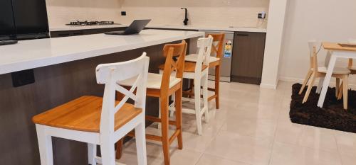 a kitchen with white chairs and a counter with a laptop at Stay in Tarneit West Melbourne in Tarneit