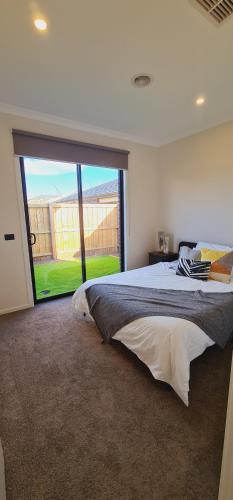 a bedroom with a large bed with a large window at Stay in Tarneit West Melbourne in Tarneit
