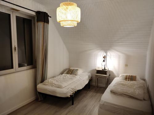 Cette petite chambre comprend 2 lits et un lustre. dans l'établissement Maison calme proche plage, jardin, wifi, animaux sur demande - FR-1-306-1290, à Mesquer